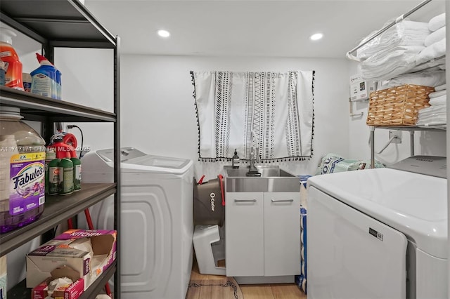 laundry room with cabinets, sink, light hardwood / wood-style flooring, and independent washer and dryer