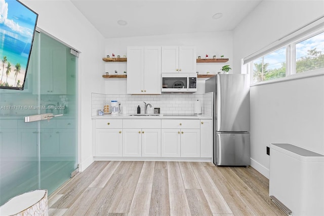 kitchen with stainless steel refrigerator, sink, light hardwood / wood-style flooring, and white cabinets