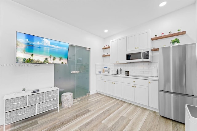 kitchen with tasteful backsplash, white cabinetry, sink, and stainless steel fridge