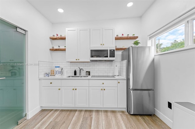 kitchen featuring sink, stainless steel refrigerator, and white cabinets