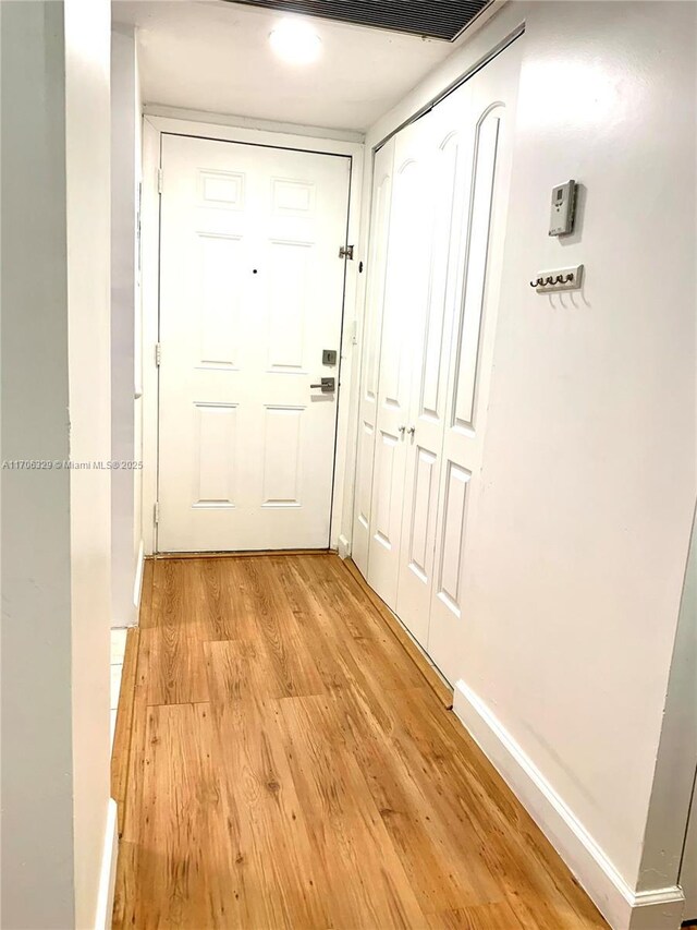 doorway with light wood-type flooring and baseboards