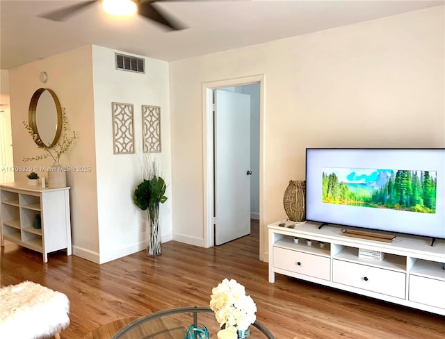 living area featuring ceiling fan, wood finished floors, visible vents, and baseboards