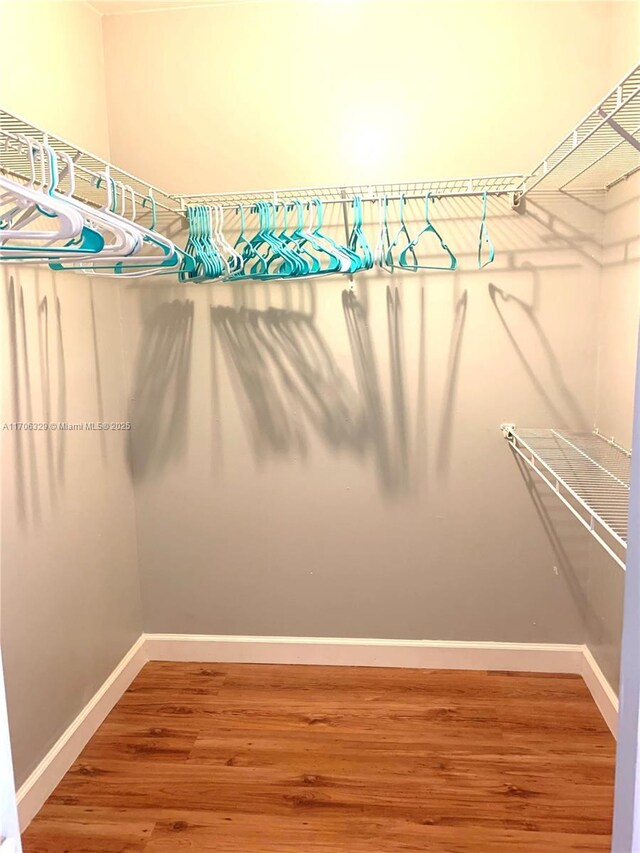 hallway featuring a sink, wood finished floors, visible vents, and baseboards