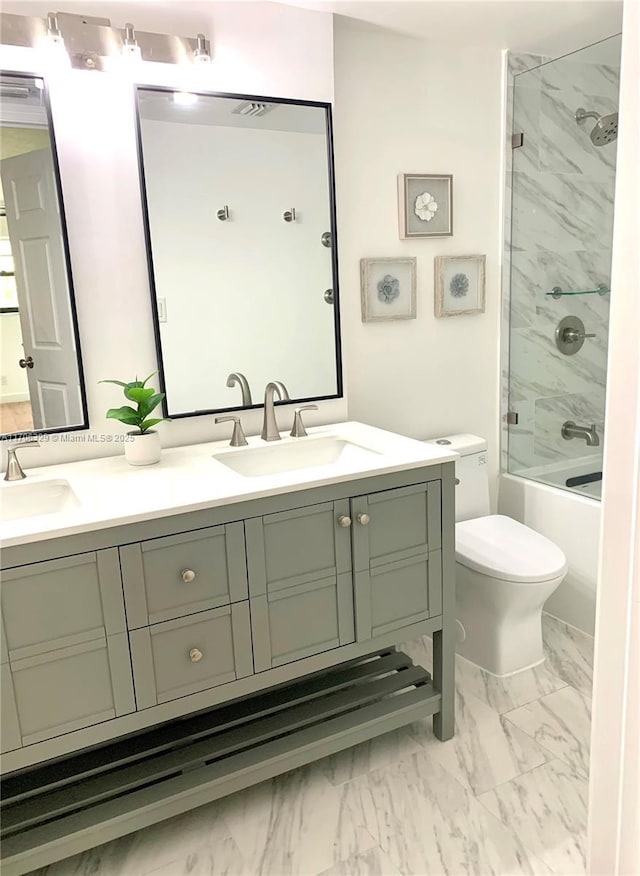 full bath featuring toilet, marble finish floor, double vanity, and a sink