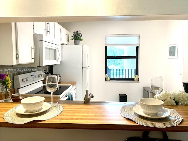 kitchen featuring tasteful backsplash, white cabinets, and white appliances