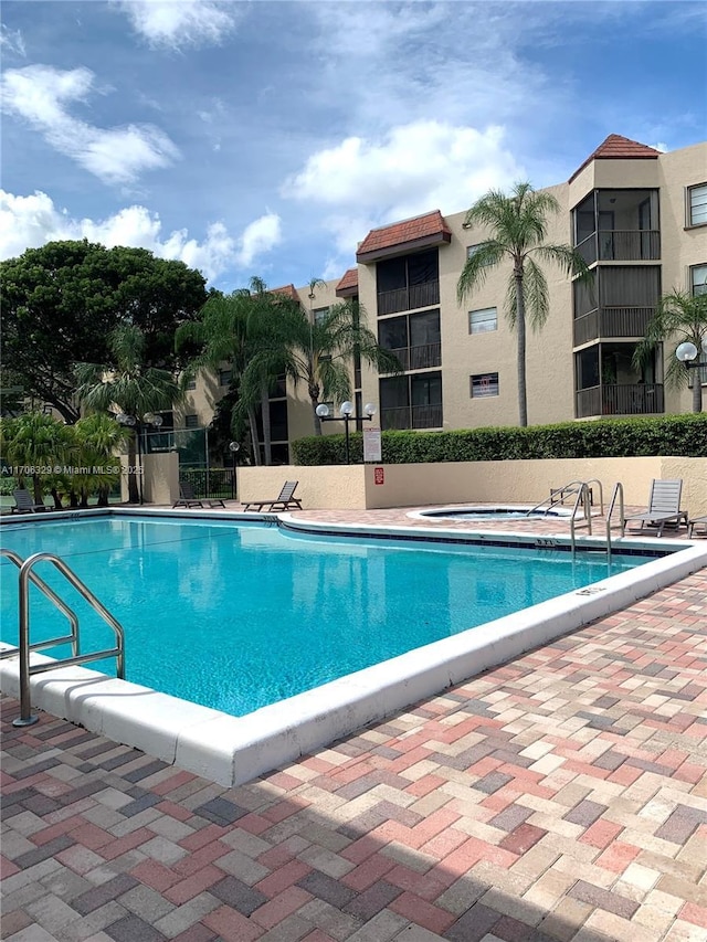 community pool with a patio area and fence