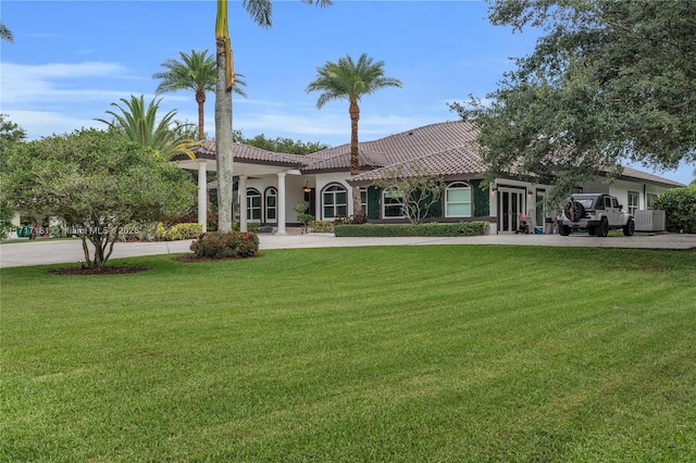 view of front of home with stucco siding, a front lawn, concrete driveway, and a tiled roof