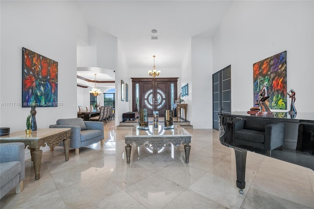 foyer with a chandelier, arched walkways, a high ceiling, and marble finish floor