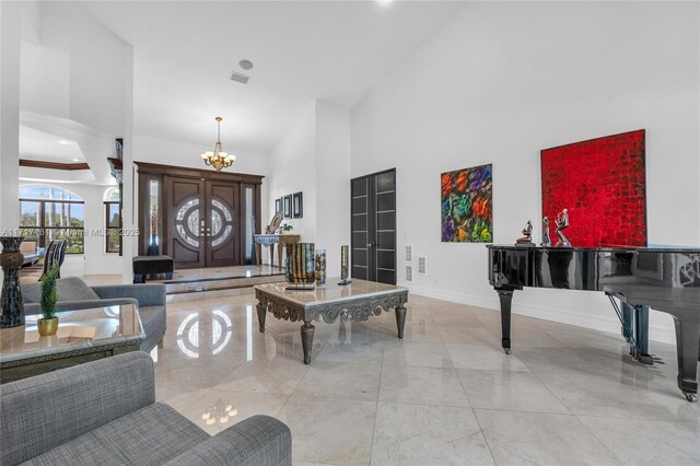 interior space with a chandelier, marble finish floor, baseboards, visible vents, and a high ceiling