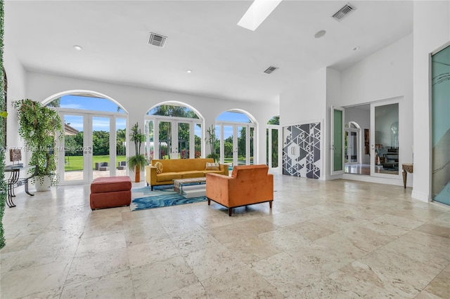 interior space featuring a skylight, french doors, visible vents, and a high ceiling