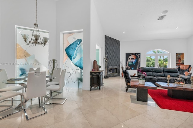 living area featuring a wood stove, visible vents, an inviting chandelier, marble finish floor, and a high ceiling
