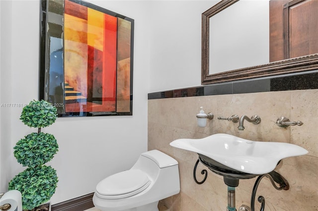 bathroom featuring toilet and tile walls