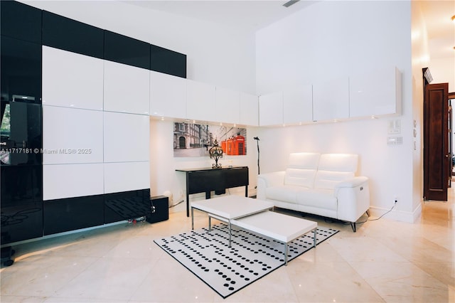 living room featuring a towering ceiling, baseboards, and light tile patterned floors