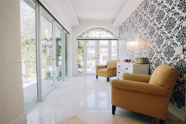 living area with an accent wall, french doors, marble finish floor, and wallpapered walls