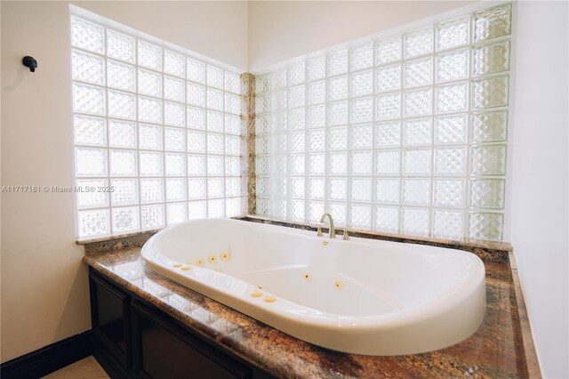 bathroom featuring a whirlpool tub and baseboards