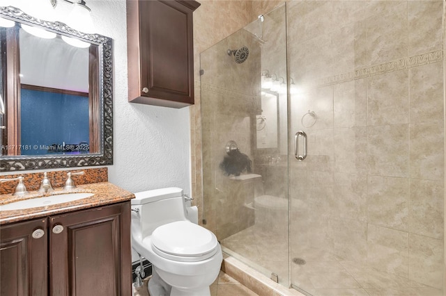 full bathroom with toilet, a textured wall, a shower stall, and vanity
