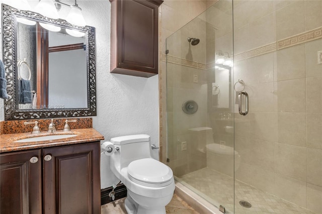 bathroom featuring a textured wall, a shower stall, toilet, and vanity