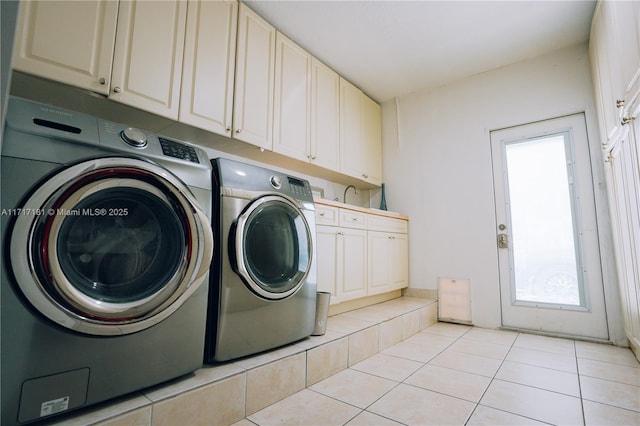clothes washing area with cabinet space, light tile patterned flooring, and washing machine and dryer