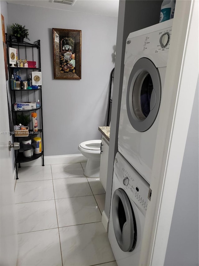 clothes washing area featuring light tile patterned floors and stacked washer / dryer