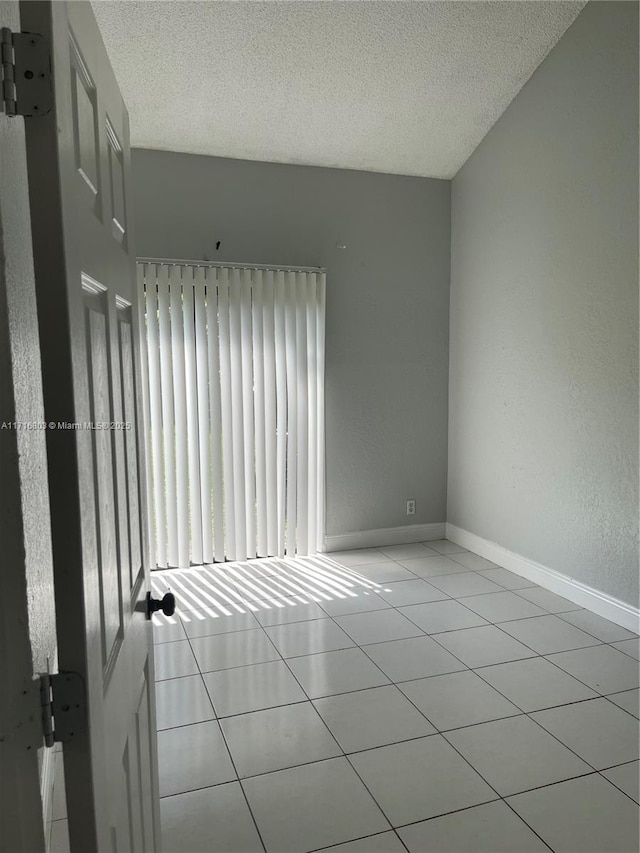 tiled empty room with a textured ceiling