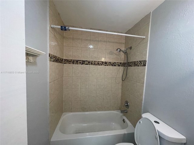 bathroom with toilet and tiled shower / bath