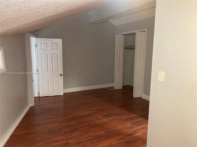 interior space with a textured ceiling, dark hardwood / wood-style flooring, and lofted ceiling with beams