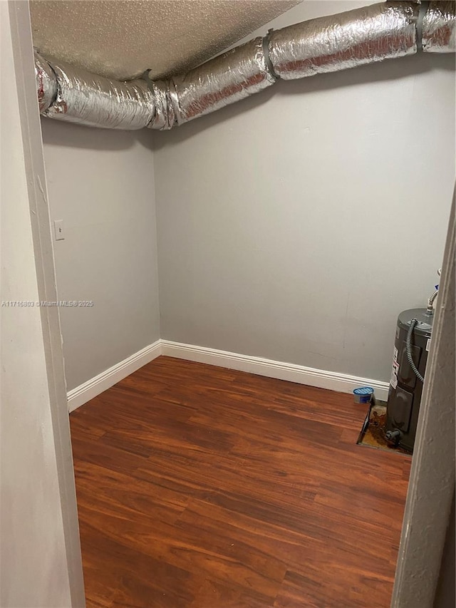 interior space with hardwood / wood-style floors, a textured ceiling, and water heater