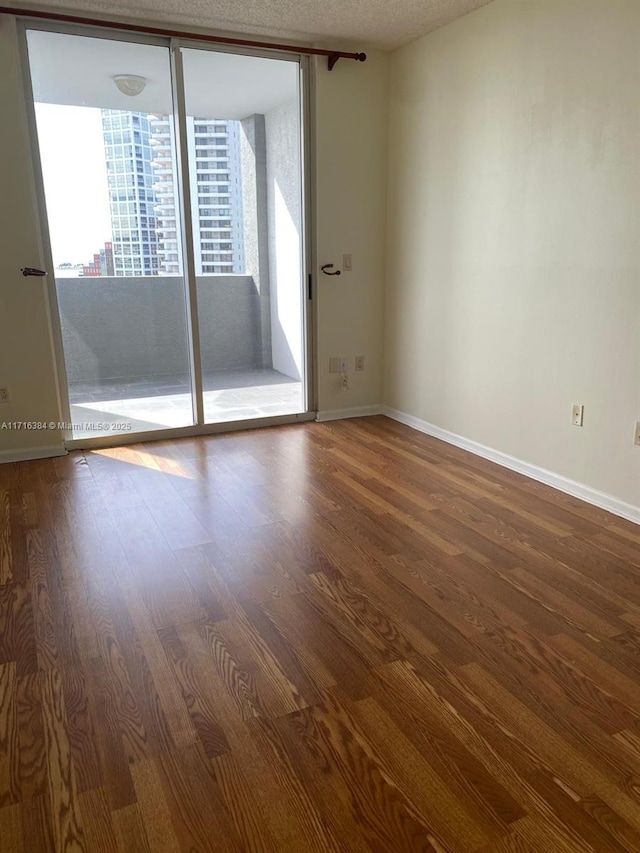 empty room featuring floor to ceiling windows, a wealth of natural light, and hardwood / wood-style floors