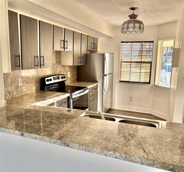 kitchen with hanging light fixtures, a textured ceiling, stainless steel appliances, and tasteful backsplash