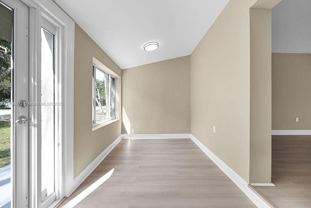 hallway featuring light hardwood / wood-style floors and vaulted ceiling