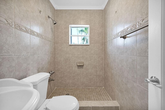 bathroom featuring a tile shower, crown molding, sink, and toilet