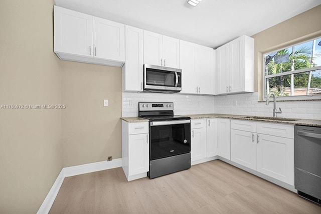 kitchen featuring light stone countertops, stainless steel appliances, white cabinetry, and sink