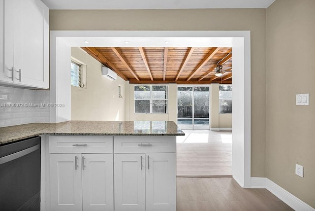 kitchen with stainless steel dishwasher, white cabinetry, wood ceiling, and a wall unit AC