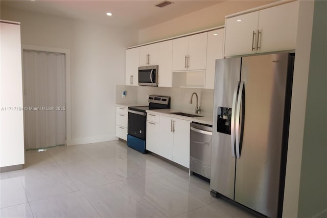 kitchen with white cabinets, sink, tasteful backsplash, light tile patterned flooring, and stainless steel appliances