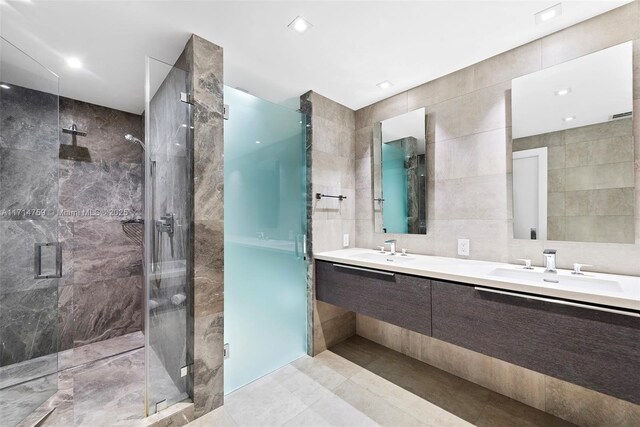 bathroom featuring tile patterned flooring, vanity, an enclosed shower, and tile walls