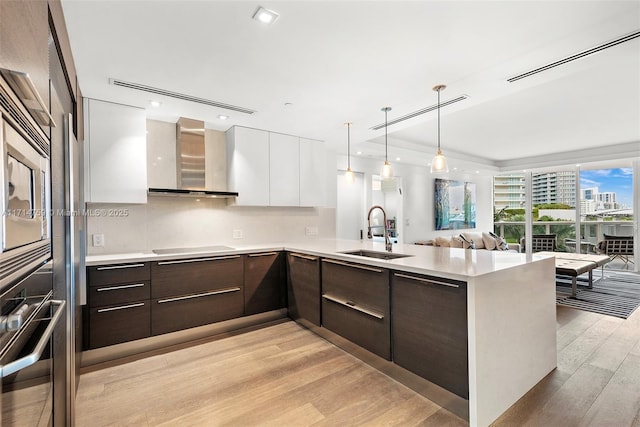 400 Alton Rd Unit 509, Miami Beach, FL 33139 - kitchen with modern cabinets, wall chimney exhaust hood, dark brown cabinetry, white cabinets, and light countertops