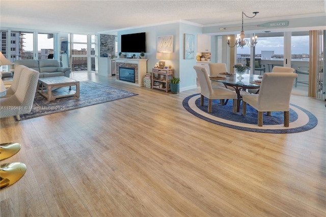 living room with a fireplace, a chandelier, plenty of natural light, and light wood-type flooring