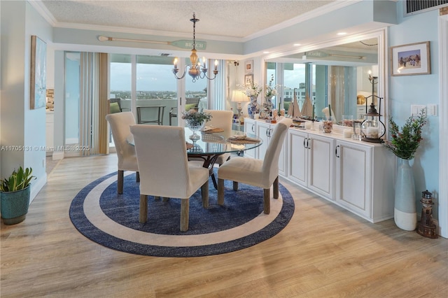 dining area featuring a chandelier, a textured ceiling, light hardwood / wood-style flooring, and ornamental molding