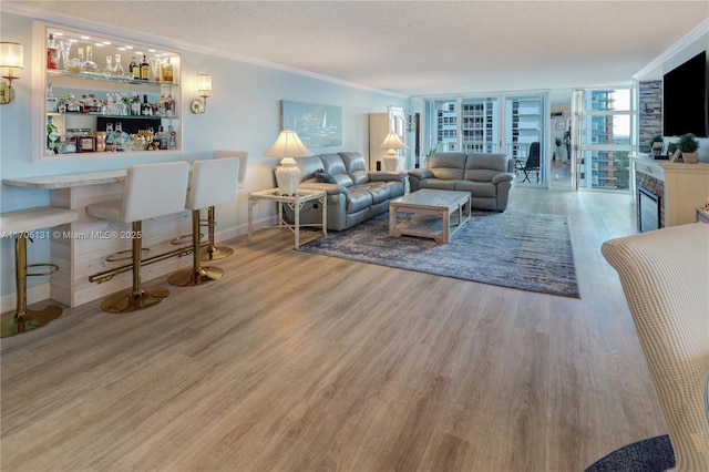 living room with indoor bar, ornamental molding, a textured ceiling, a fireplace, and wood-type flooring