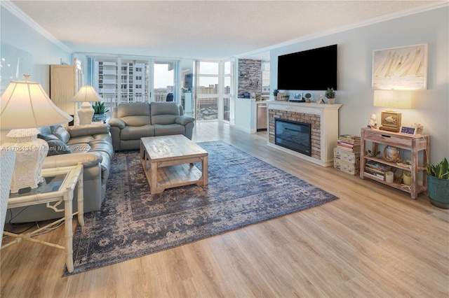 living room with floor to ceiling windows, light hardwood / wood-style flooring, ornamental molding, a textured ceiling, and a fireplace