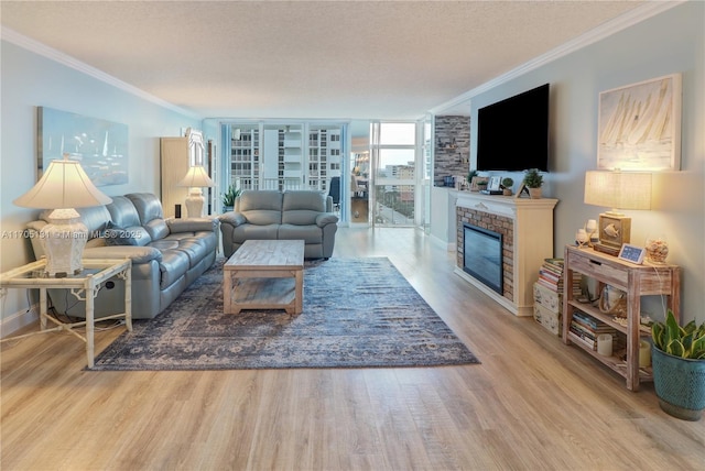 living room featuring a brick fireplace, expansive windows, a textured ceiling, crown molding, and hardwood / wood-style floors