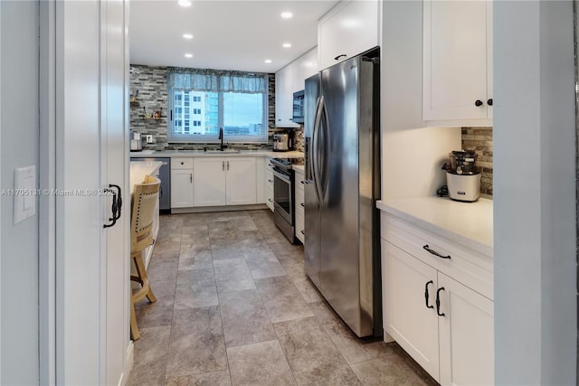 kitchen with backsplash, white cabinetry, sink, and stainless steel appliances