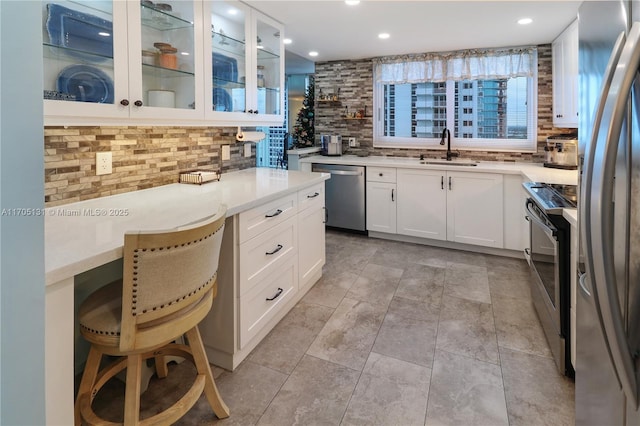 kitchen featuring sink, a kitchen breakfast bar, backsplash, white cabinets, and appliances with stainless steel finishes