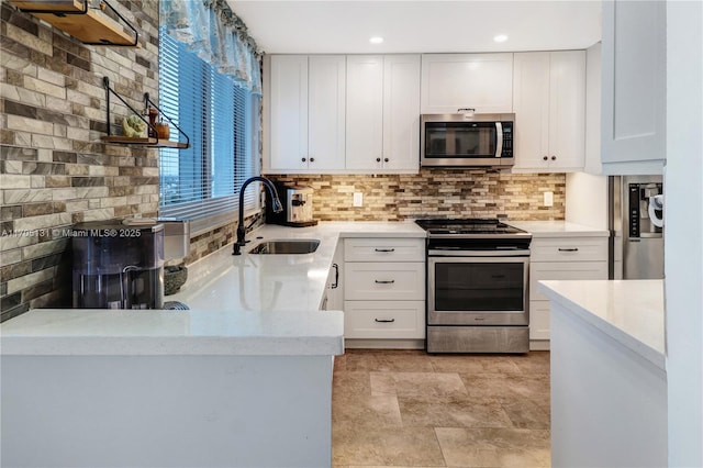 kitchen with kitchen peninsula, backsplash, stainless steel appliances, sink, and white cabinetry