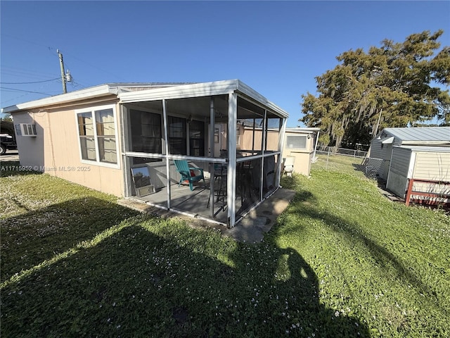 back of house with a sunroom, a shed, a patio, and a lawn