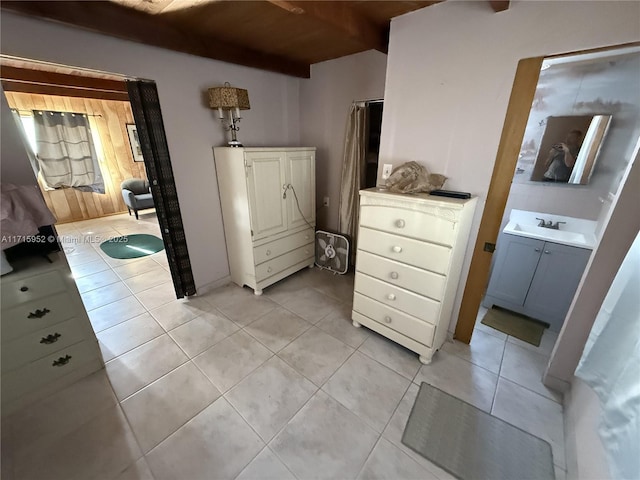 interior space with light tile patterned flooring, sink, wooden ceiling, and beam ceiling