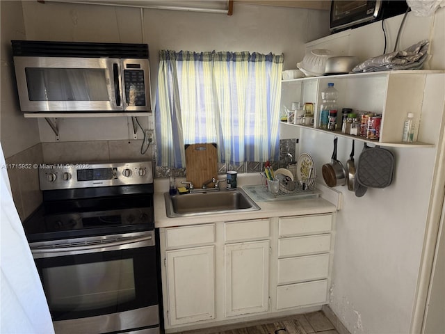 kitchen featuring white cabinets, stove, and sink