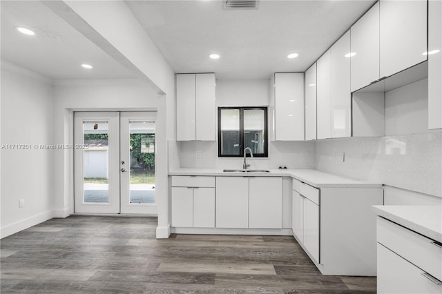 kitchen with french doors, sink, ornamental molding, tasteful backsplash, and white cabinetry