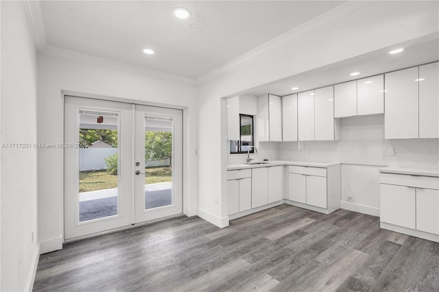 kitchen featuring sink, french doors, crown molding, white cabinets, and light wood-type flooring