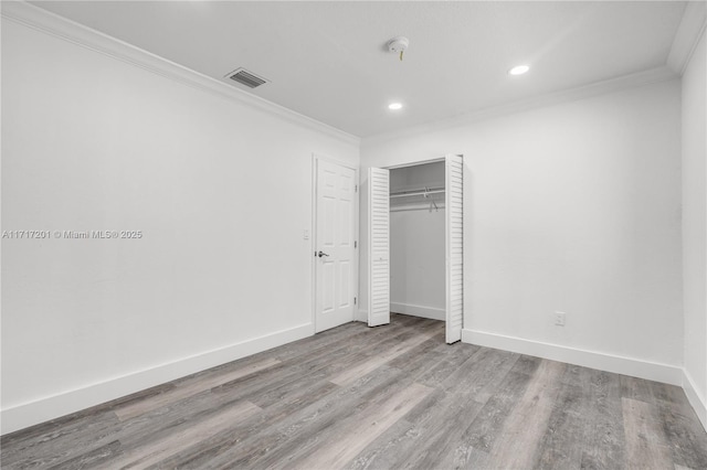 unfurnished bedroom with light hardwood / wood-style floors, a closet, and crown molding